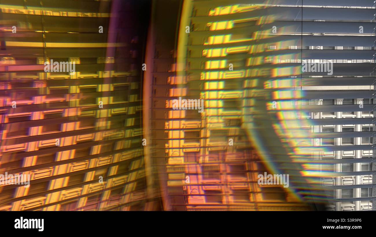 Farbenfrohes, abstraktes Muster mit Prisma vor dem Kameraobjektiv. Wiederholte, überlappende Bilder der Gebäudefassade, die durch Jalousien gesehen werden - Smartphone-aufgenommenes Stockfoto