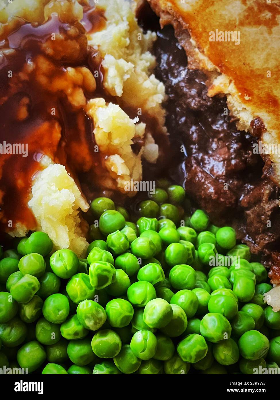 ‘Pie & Mash’ Nahaufnahme eines leckeren Steak Pie mit Kartoffelpüree, Erbsen und dicker Soße Stockfoto