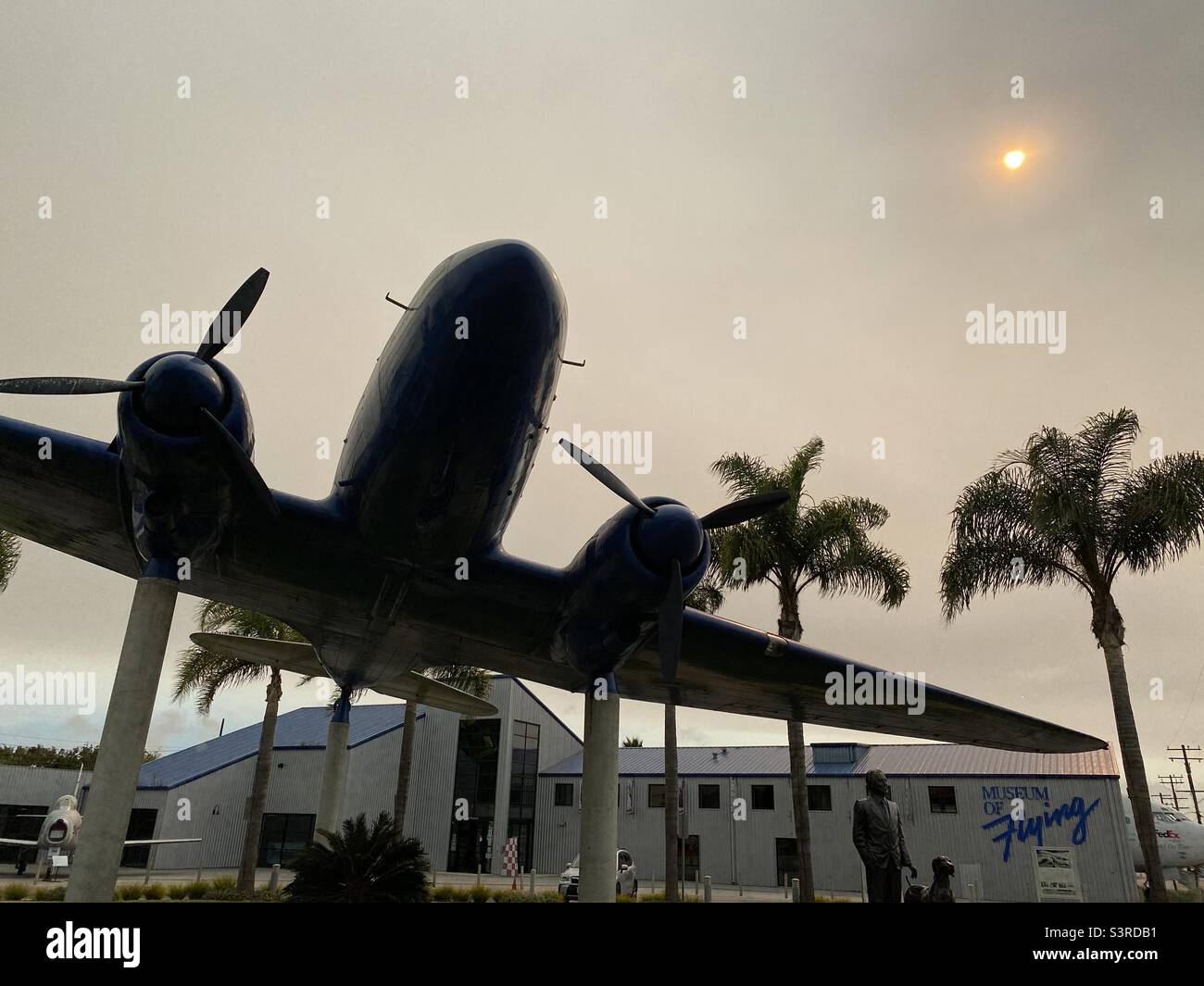 LOS ANGELES, CA, SEP 2021: Douglas DC3 Monument mit Palmen vor dem Museum of Flying am Santa Monica Municipal Airport, verschwommener Nachmittag mit niedriger, schwacher Sonne Stockfoto