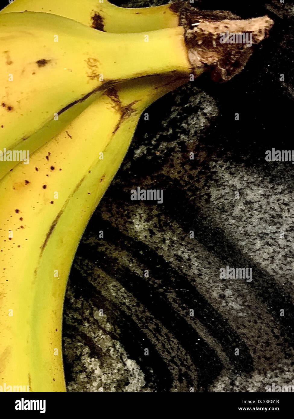 3 reife Bananen auf schwarzem Marmorboden mit Kopierraum - Smartphone-aufgenommenes Stockfoto