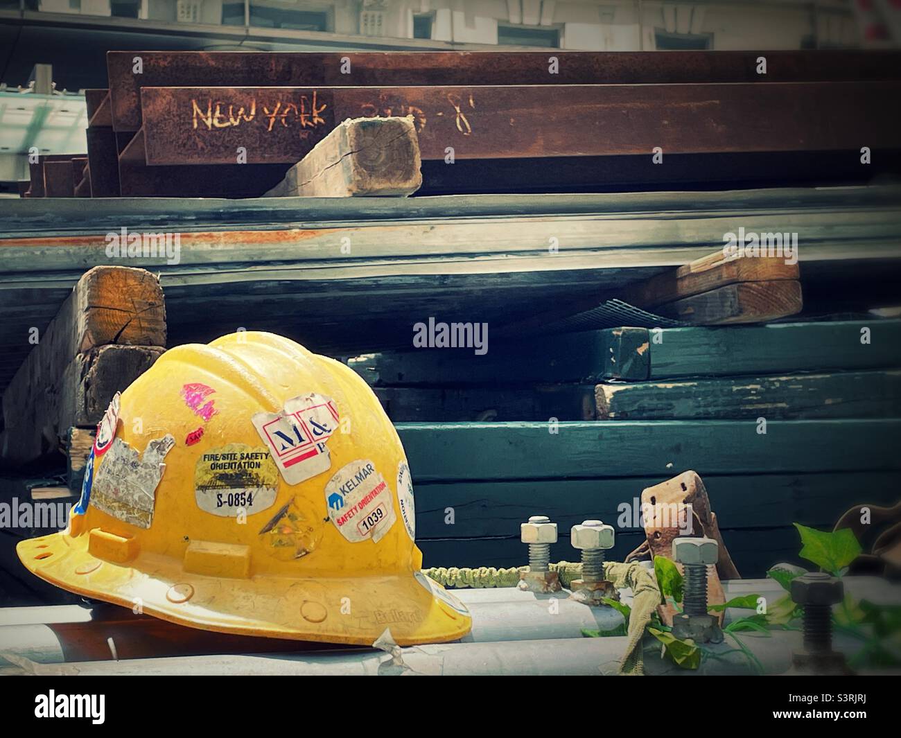 Nahaufnahme eines gelben Hardhuts von Bauarbeitern auf einem Stahlträger auf einer Baustelle in Midtown Manhattan, New York City, USA, 2022 - Smartphone-aufgenommenes Stockfoto