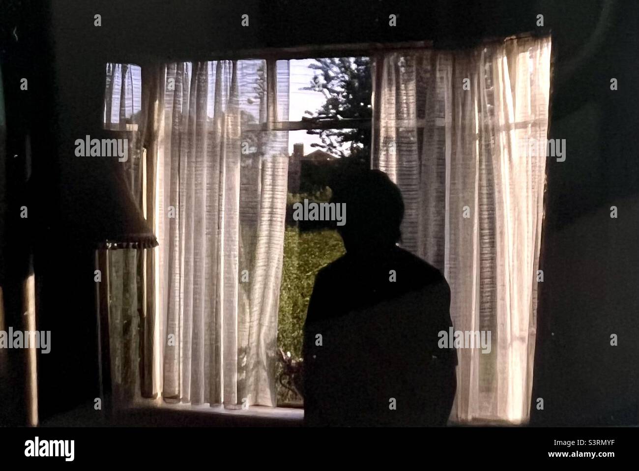 Ältere Frau, die aus dem Fenster des Hauses schaut Stockfoto