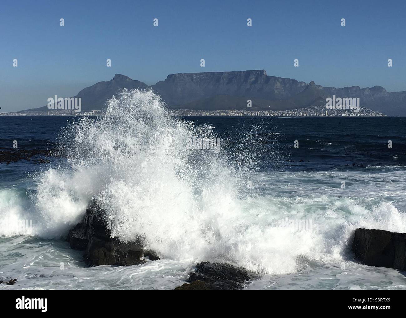 Rasende Wellen auf Robben Island mit Blick auf den Tafelberg Kapstadt - Smartphone-aufgenommenes Stockfoto