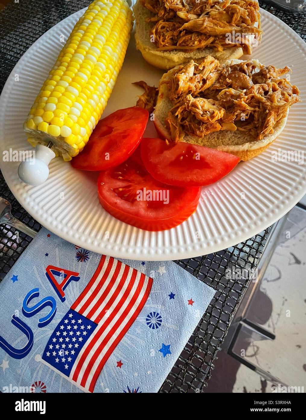 Ein Fest am 4. Juli mit gegrilltem Hähnchensandwich, frischen, reifen Tomaten und Mais auf der Maiskolben, 2022 Vereinigte Staaten von Amerika, USA Stockfoto