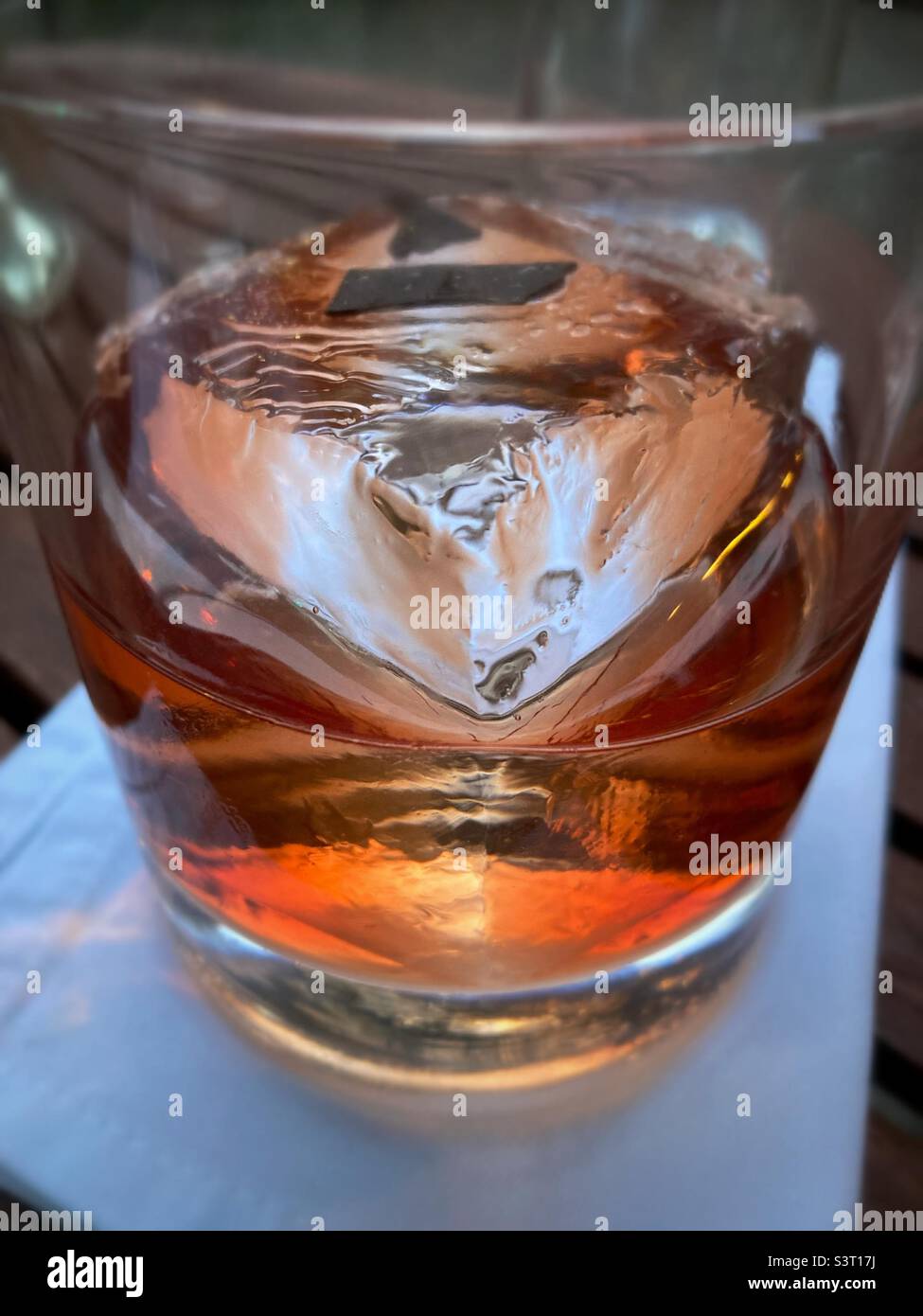 Ein halbfertiger Cocktail mit einem großen Eiswürfel Stockfoto