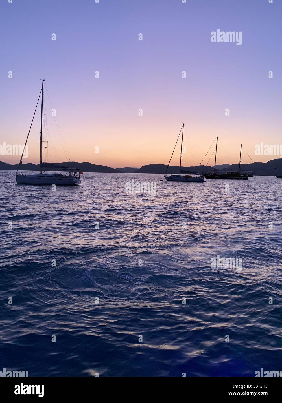 Sonnenuntergang und begleitende Boote auf See an einem Sommertag. Stockfoto