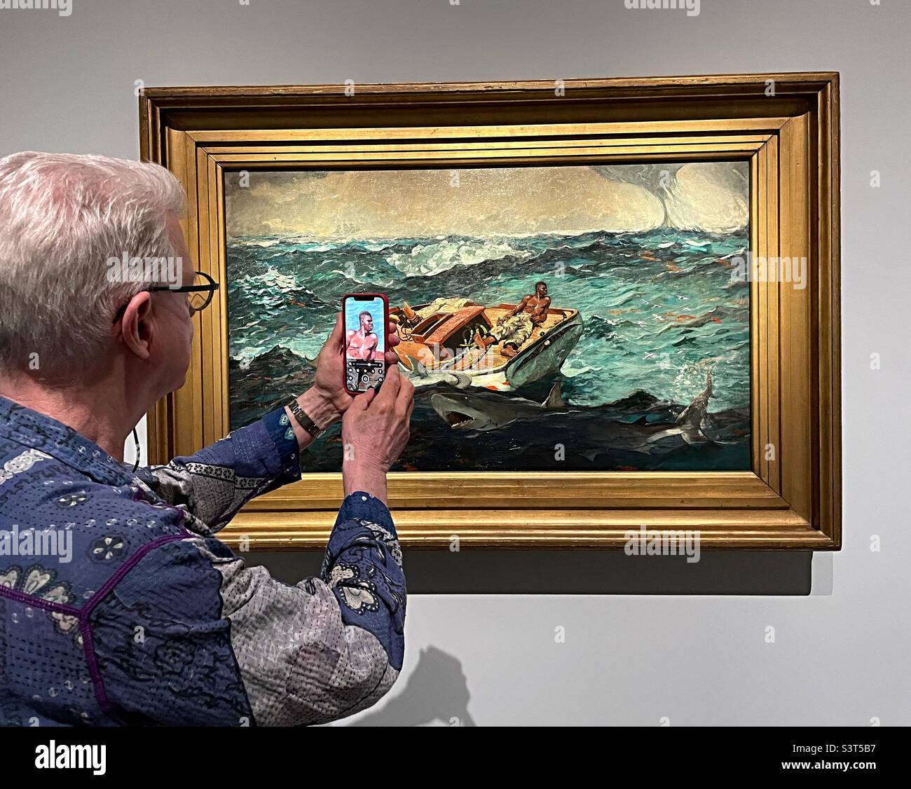 Ein älterer männlicher Mäzen, der sein iPhone benutzt, um die Details eines Homer-Winslow-Gemäldes im Metropolitan Museum of Art, 2022, New York City, USA, zu untersuchen - Smartphone-aufgenommenes Stockfoto