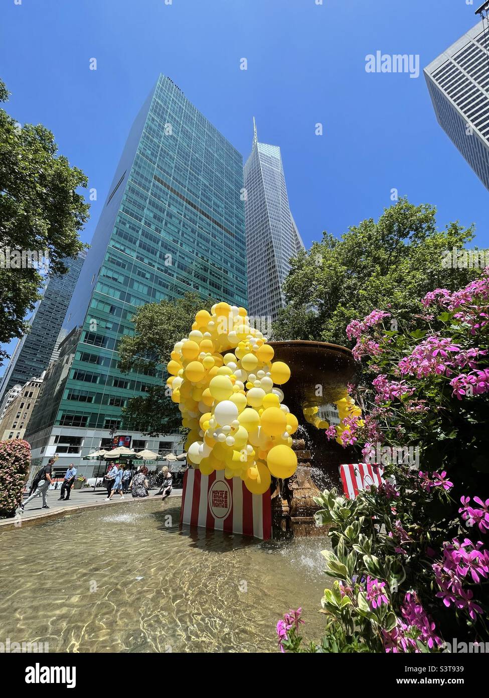 Eine Ansammlung von leuchtend gelben Ballons im Springbrunnen des Bryant Park mit Wolkenkratzern im Hintergrund, New York City, USA - Smartphone-aufgenommenes Stockfoto