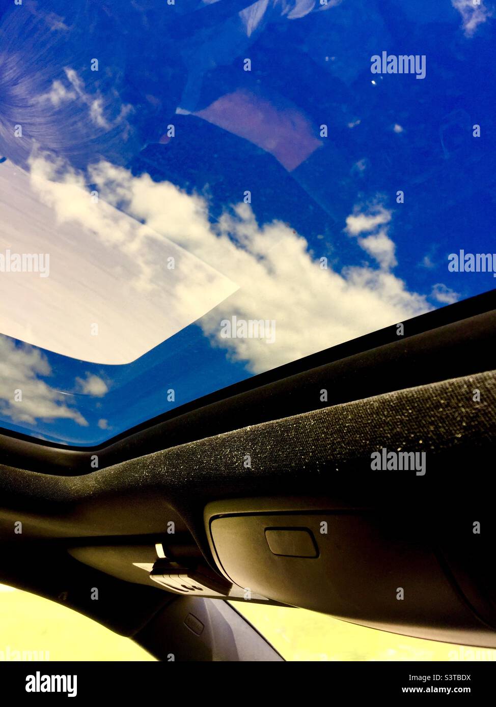 Blauer Himmel durch das Schiebedach, der Boden durch das Fenster. Freude am Fahren auf offener Straße in einem Auto mit übergroßem Dach. Québec, Kanada Stockfoto