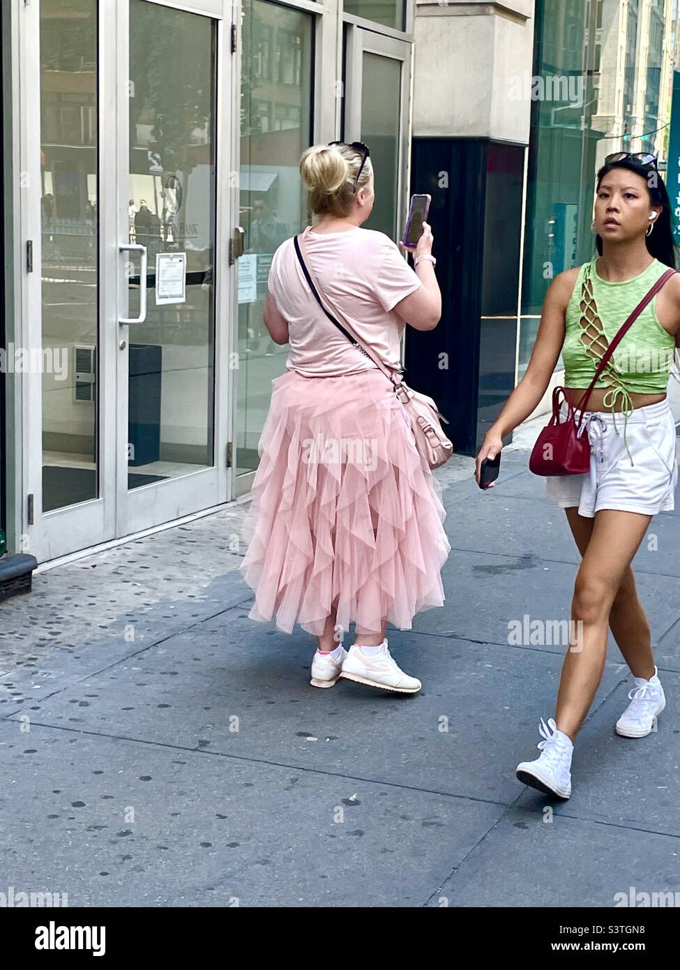 Zwei junge Frauen passieren die Straßen von New York City - Smartphone-aufgenommenes Stockfoto