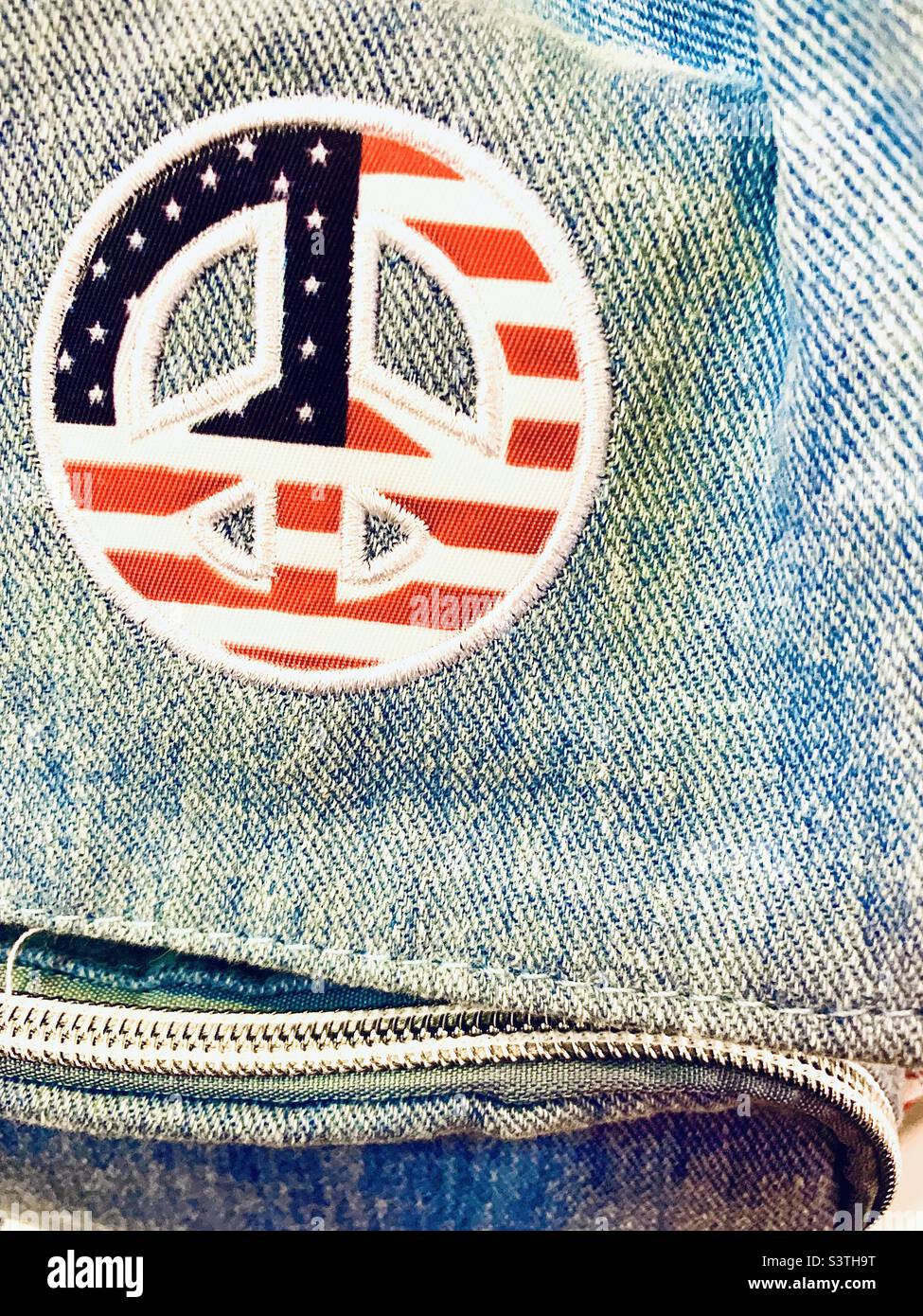 US-Flagge Friedensschild auf Denim-Hintergrund mit Reißverschluss - Smartphone-aufgenommenes Stockfoto