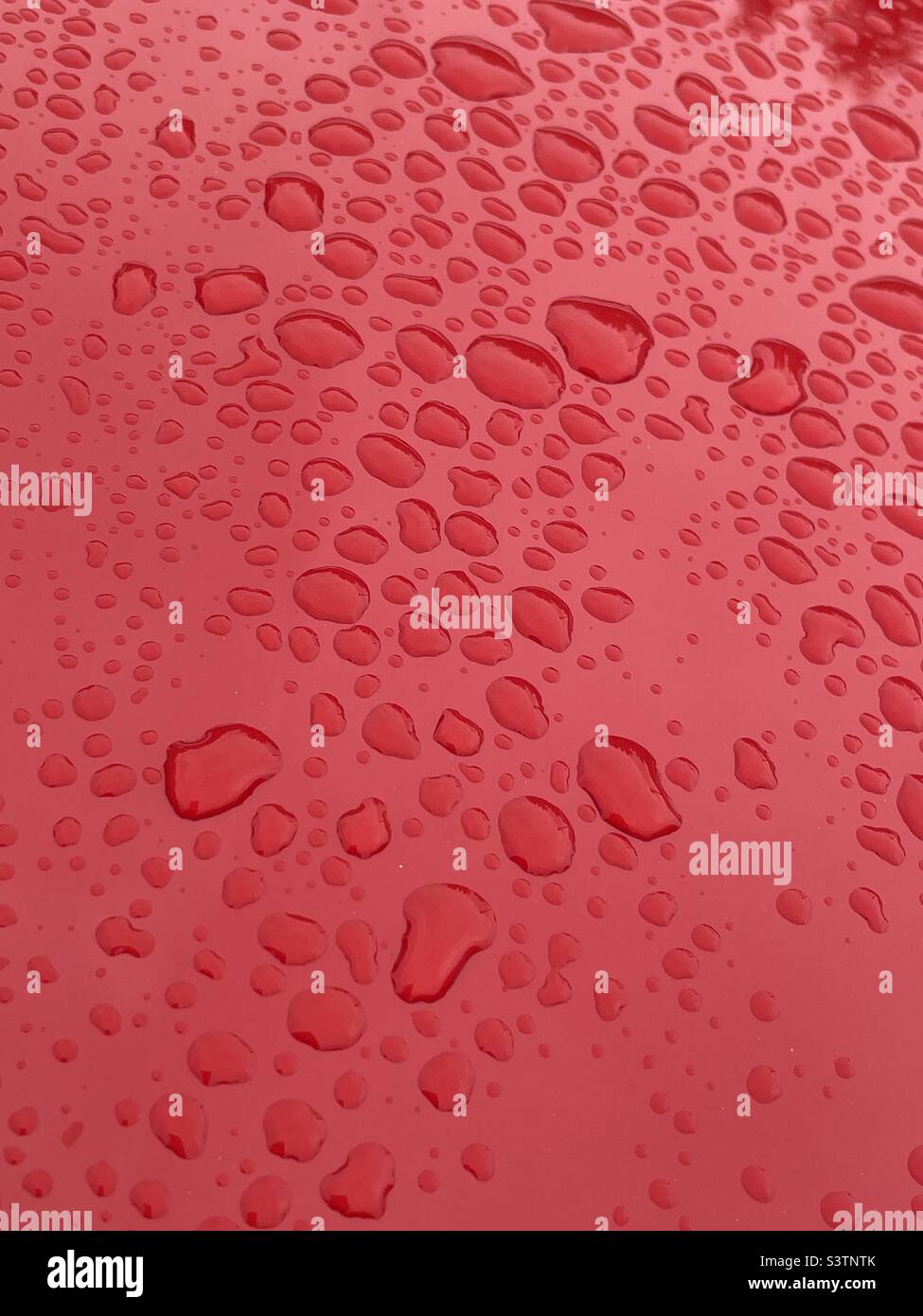 Regentropfen auf rotem Auto Stockfoto