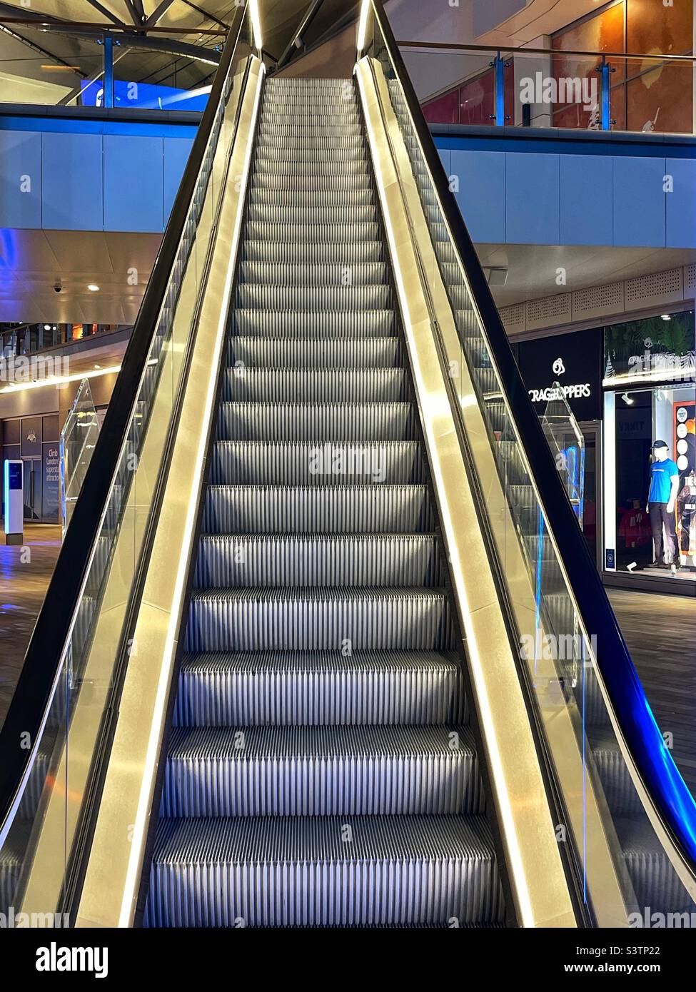 Rolltreppe in einem Einkaufszentrum, beleuchtet von Fußleuchten. Keine Personen. Stockfoto