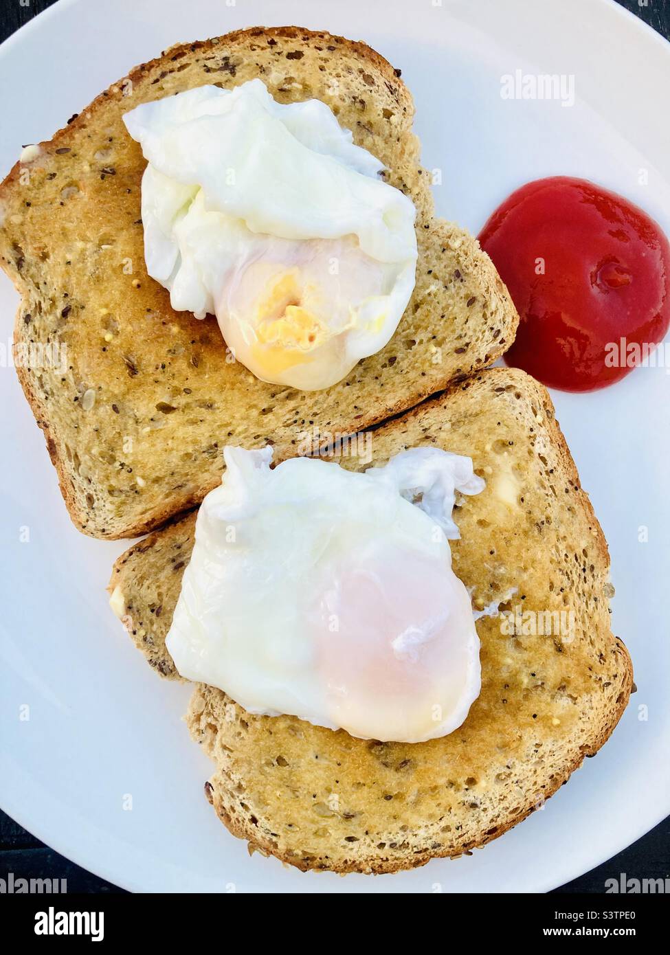 Pochierte Eier werden auf einem Vollkorntoast mit Tomatensauce serviert Stockfoto