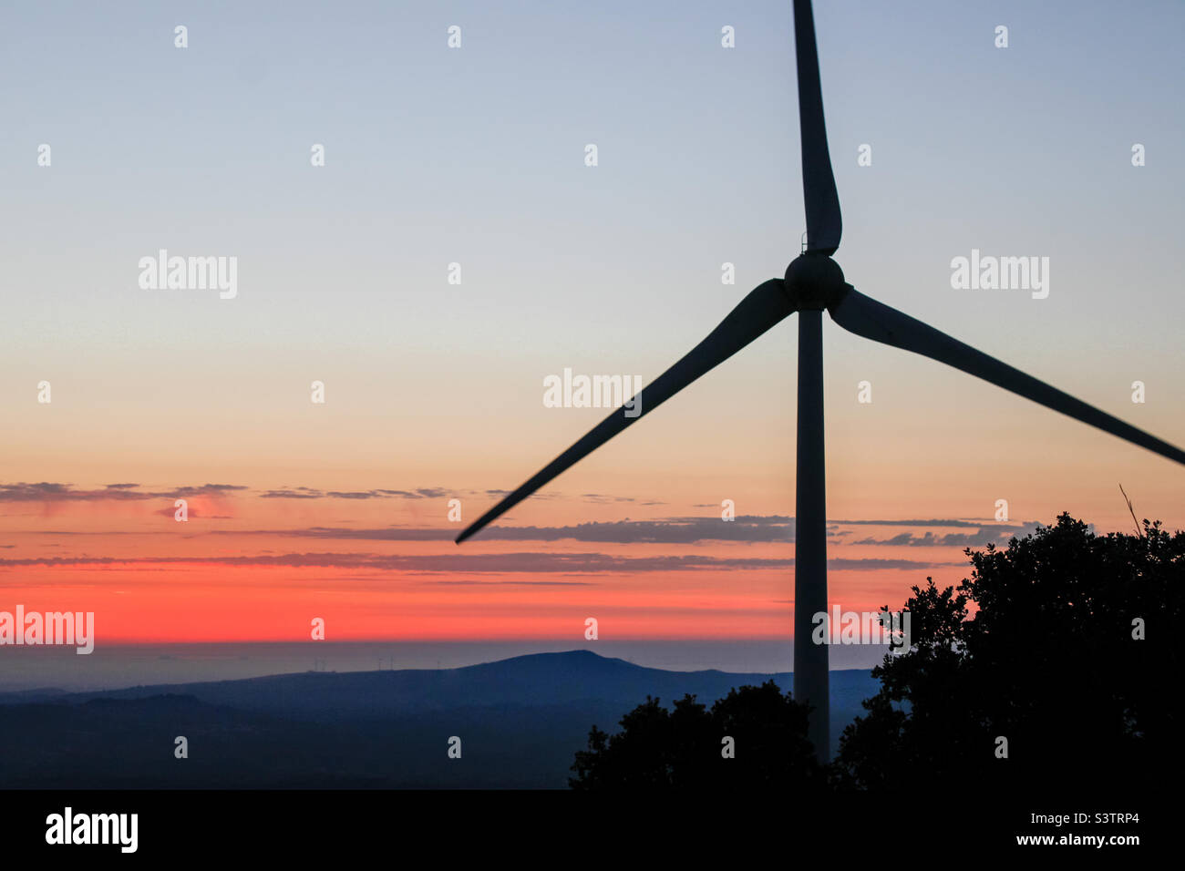 Eine Windturbine, die vom frühen Abendhimmel silhouettiert wird - Smartphone-aufgenommenes Stockfoto