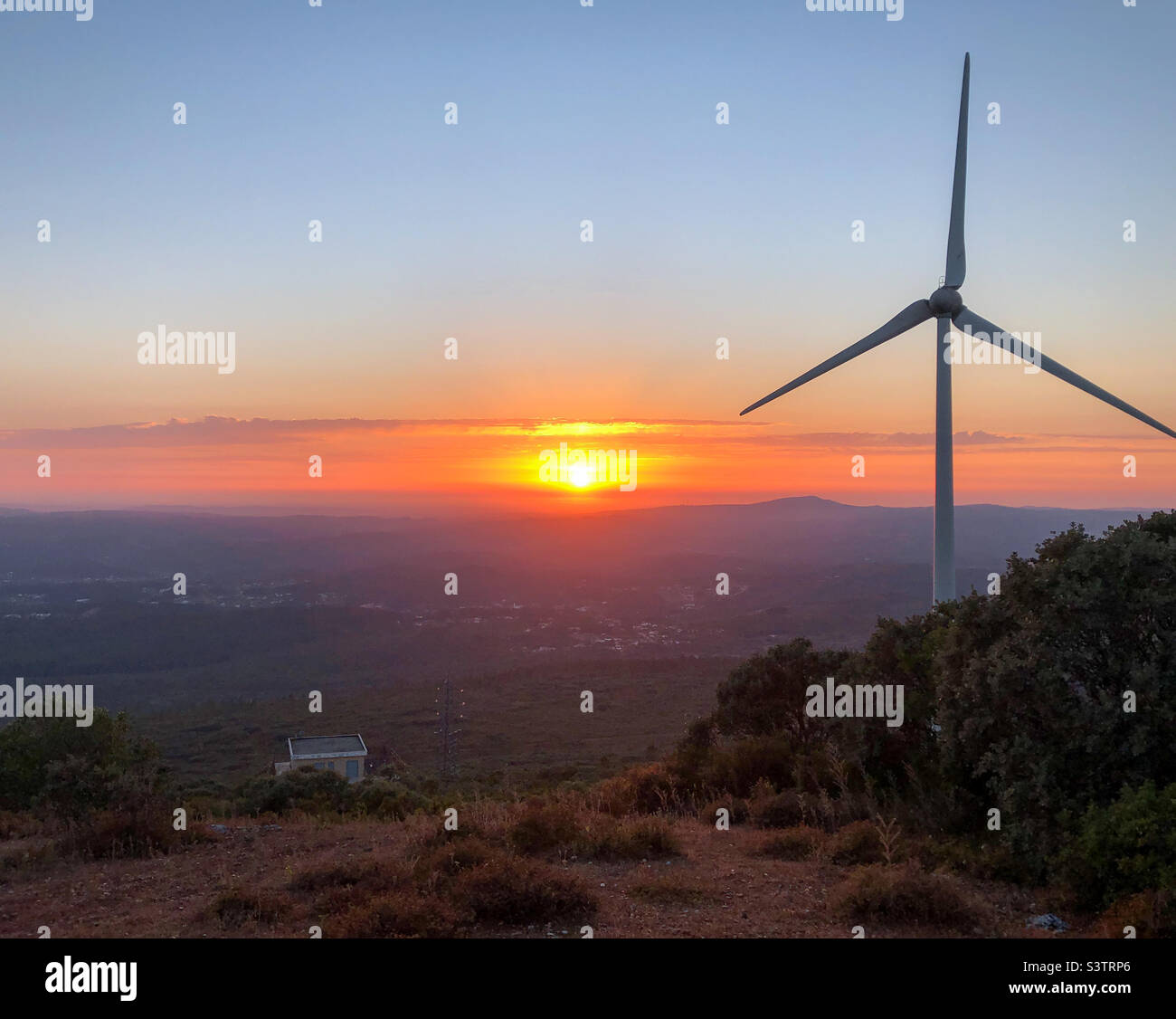 Eine Windturbine blickt über den Sonnenuntergang im Tal unten in Zentralportugal - Smartphone-aufgenommenes Stockfoto