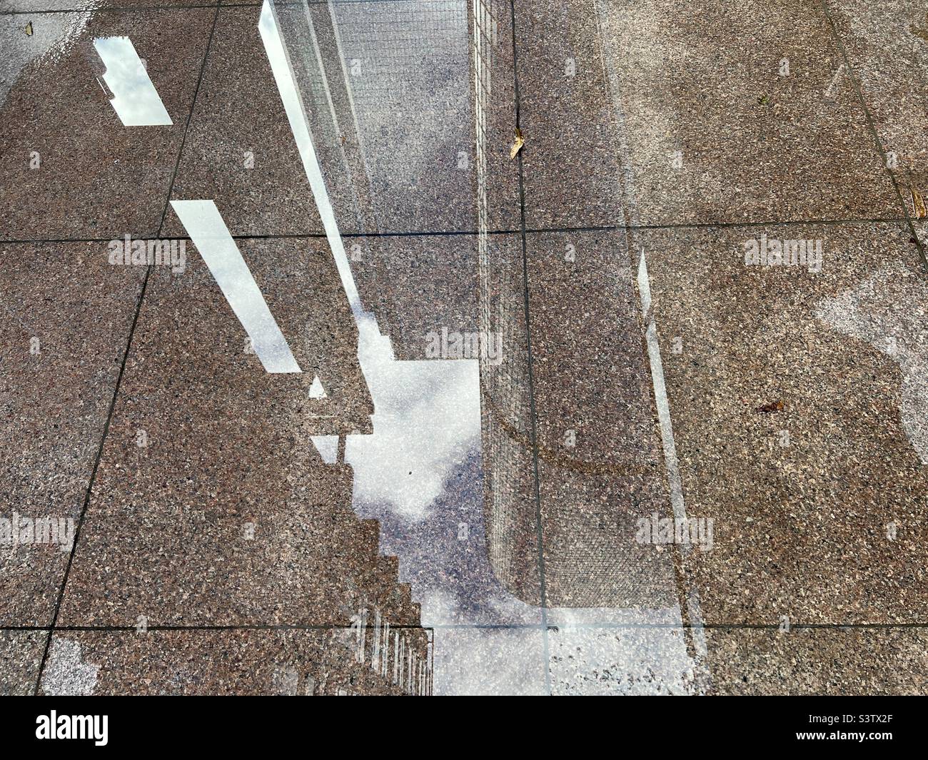 Wolkenkratzer spiegeln sich in einer Wasserpfütze auf Marmorfliesen Stockfoto