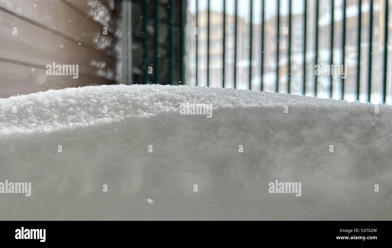 Makrodetails von Schneeflocken, die sich vor einer Glastür auftürmen, mit einem weichen Hintergrund Stockfoto