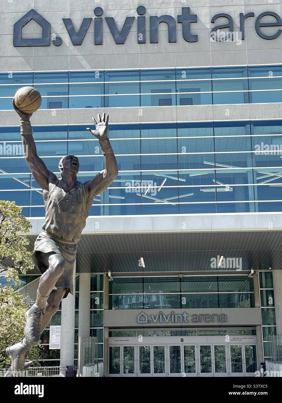 Die Vorderseite der Vivint Arena in SLC, Utah, USA, die Heimat des NBA-Teams, des Utah Jazz. Hier ist eine der beiden davor errichteten Bronzestatuen berühmter ehemaliger Spieler zu sehen: Karl Malone. - Smartphone-aufgenommenes Stockfoto