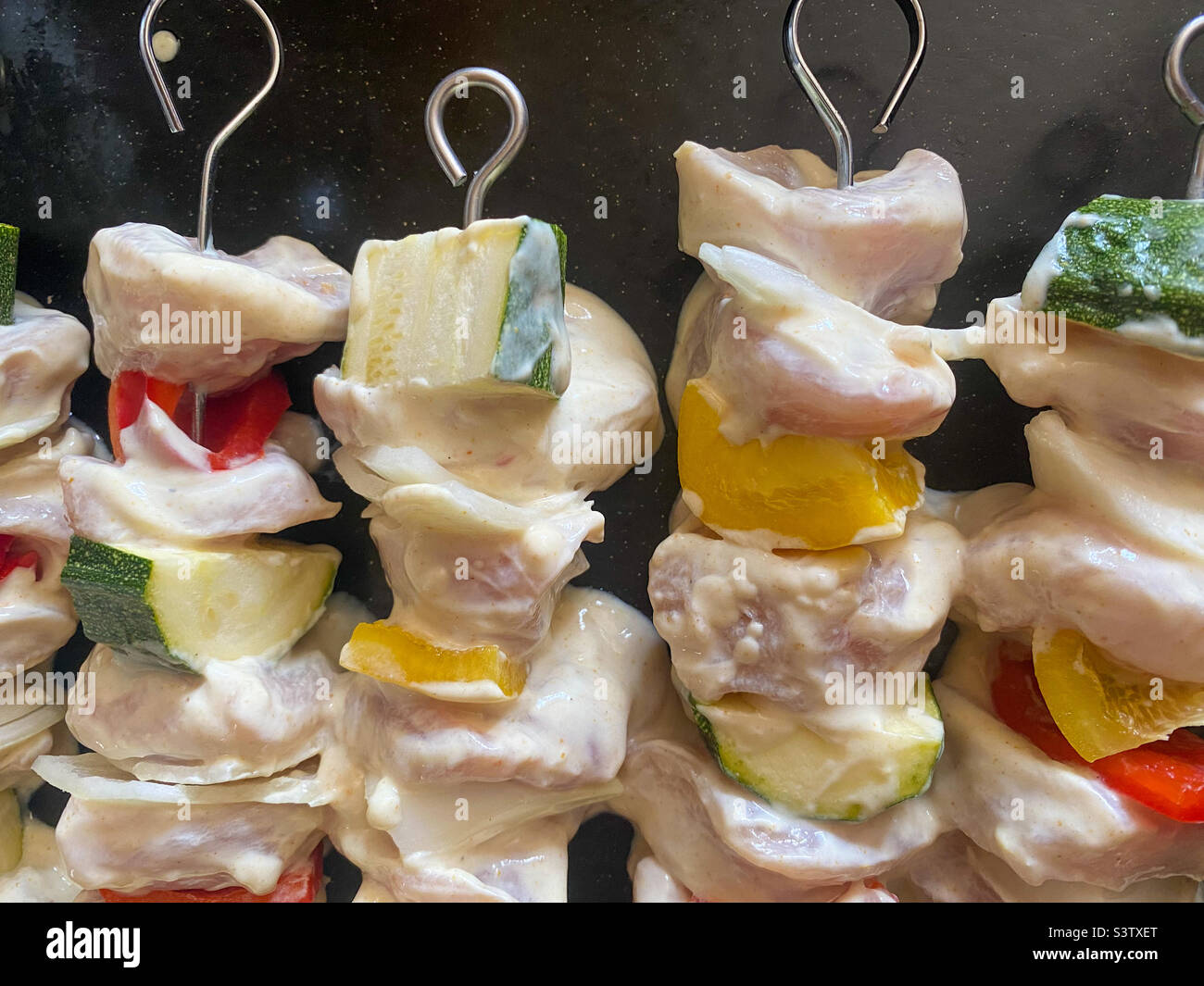 Mariniertes rohes Huhn und Gemüse auf Metallspießen, die hausgemachte Kebabs bilden. Stockfoto