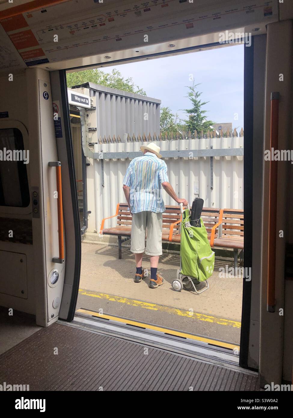 Der Mann im Sommeroutfit steigt aus dem London Overground Zug aus Stockfoto