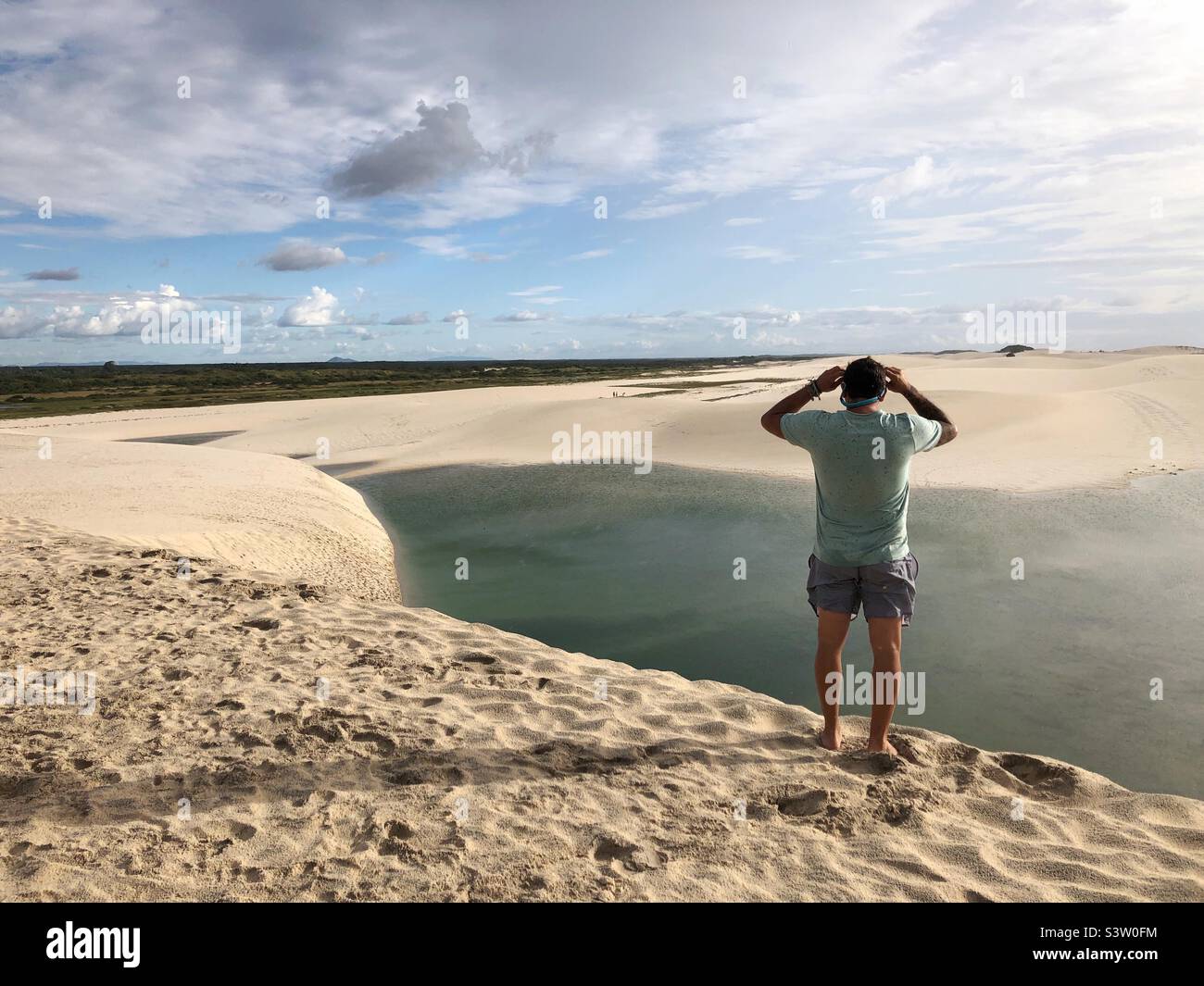 Ein Mann, der in den Dünen steht und auf die natürliche Lagune blickt. Stockfoto