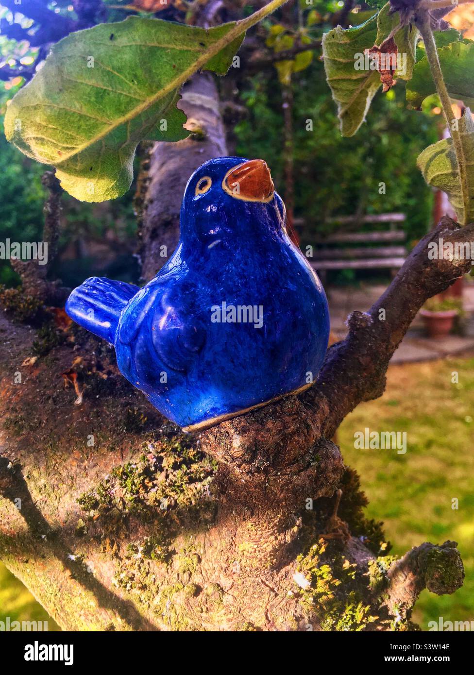 Blauer Keramikvogel in einem Apfelbaum Stockfoto