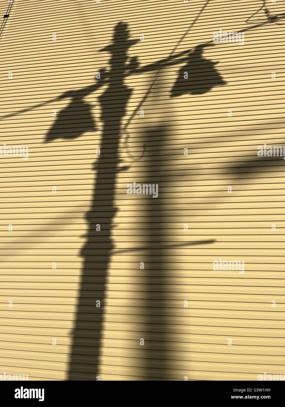 Lampenschatten an gelber Holzwand Stockfoto