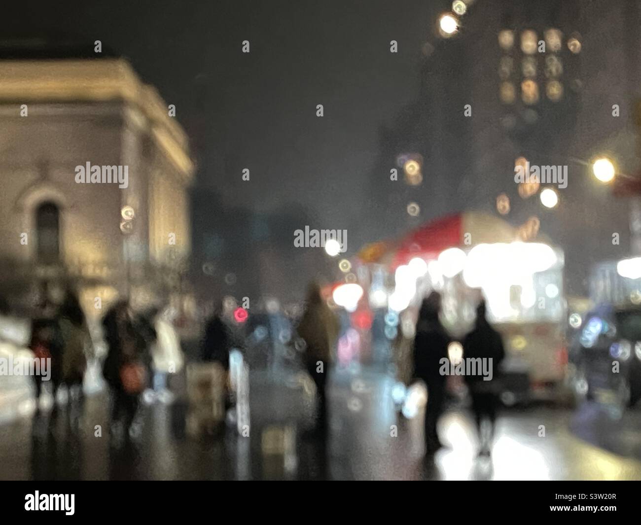 Geheimnisvolle Silhouetten, die bei Nacht entlang der 5th Avenue, NYC, spazieren, mit filmischer Atmosphäre und lebendiger urbaner Energie. - Smartphone-aufgenommenes Stockfoto