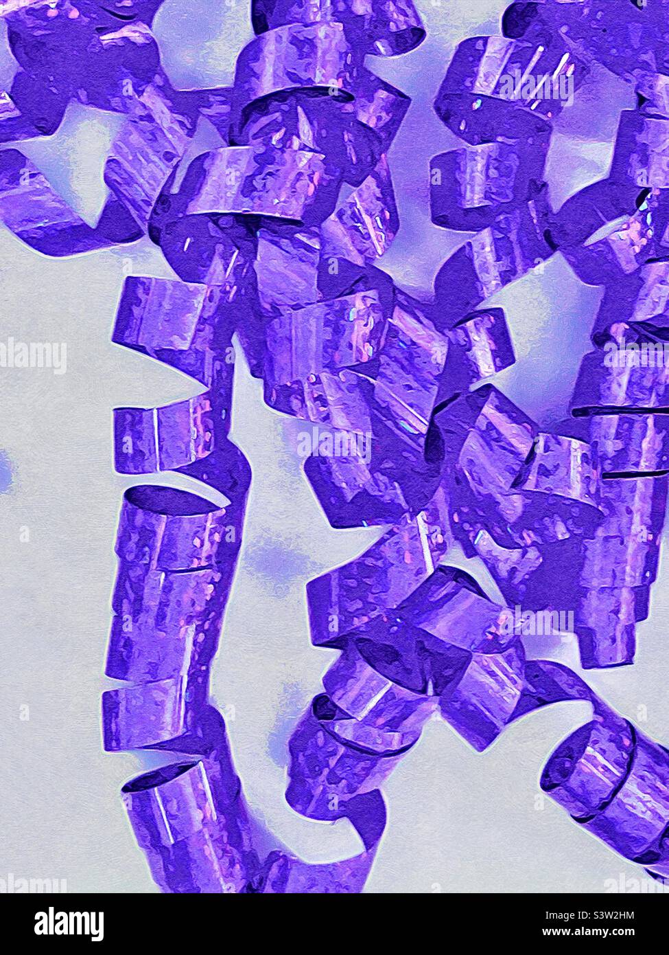 Ein lockiges und glitzerndes violettes Band, das für Geschenkverpackungen oder Dekorationen für Partys und Feiern verwendet wird, bildet einen festlichen, strukturierten Abstrakt vor weißem Hintergrund. - Smartphone-aufgenommenes Stockfoto
