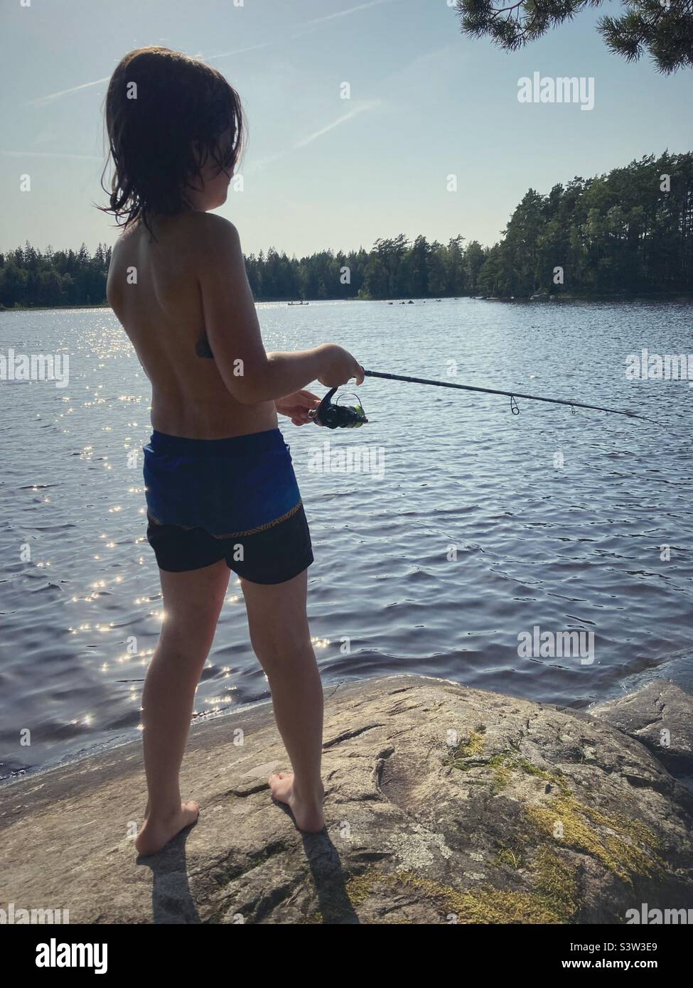 Ein neun bis zehn Jahre alter Junge, der im Sommer in einem See in smaland, Schweden, angeln kann Stockfoto