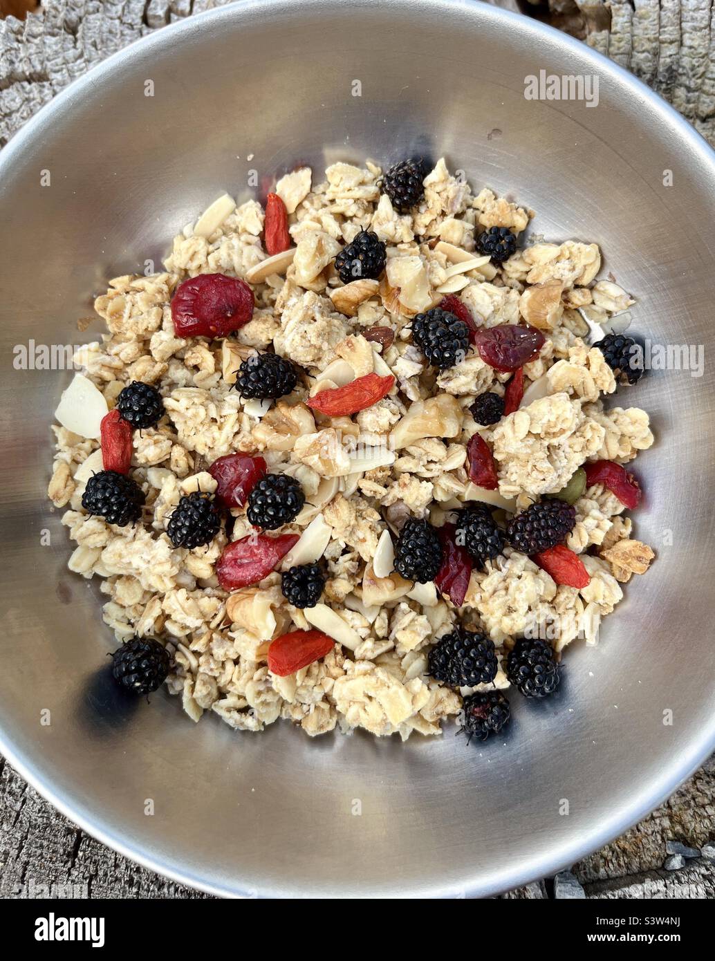 Eine Schüssel veganes Müsli mit Preiselbeeren, Goji-Beeren und frischen Maulbeeren - Smartphone-aufgenommenes Stockfoto