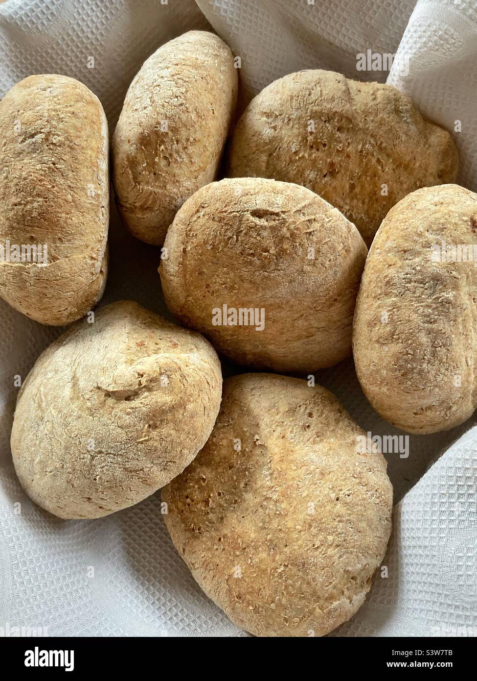 Ein Korb mit frisch gebackenen rustikalen Brötchen - Smartphone-aufgenommenes Stockfoto