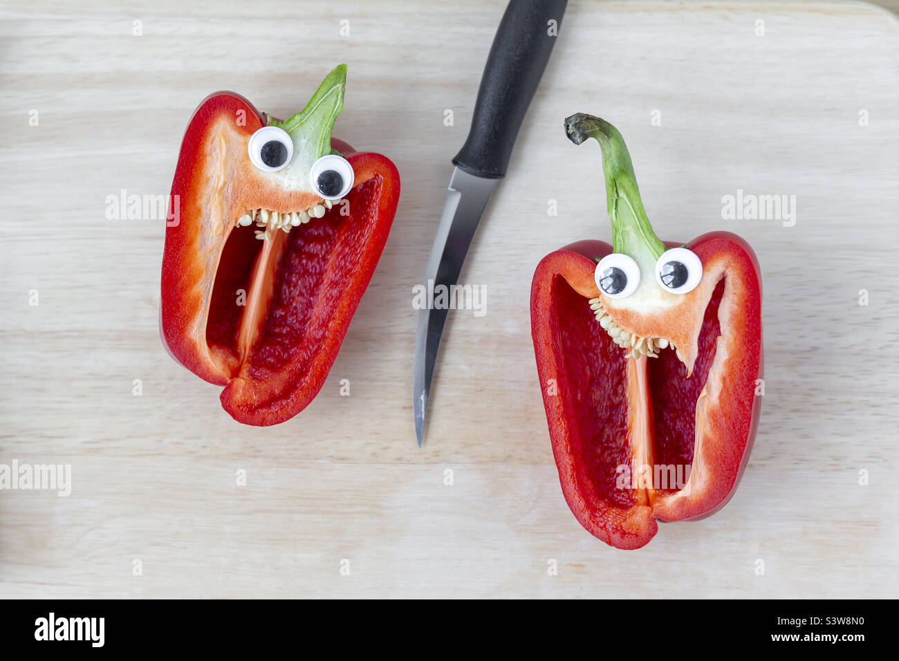 Paprika in zwei Hälften geschnitten mit Messer in der Mitte des Rahmens, gute Augen - Smartphone-aufgenommenes Stockfoto
