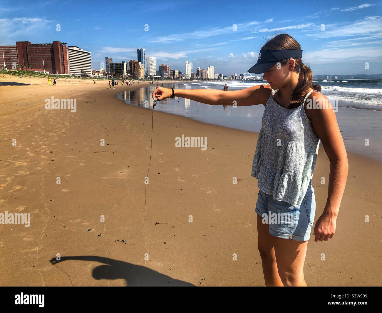 Junges Mädchen, das während einer Blauflaschen-Invasion am Hauptstrand von Durban eine Blauflasche mit einem langen Tentakel hält Stockfoto