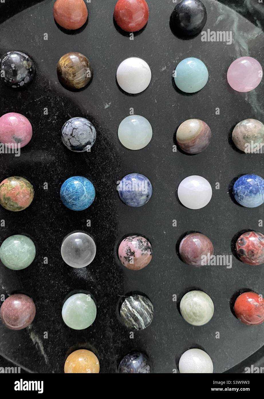 Eine oben und gezoomte Ansicht eines aus Stein, Onyx-Marmor gefügten Chinese Checker Spielbretts. Bildet eine symmetrische und geordnete Zusammenfassung mit Farbtupfen, Design und Textur. Stockfoto