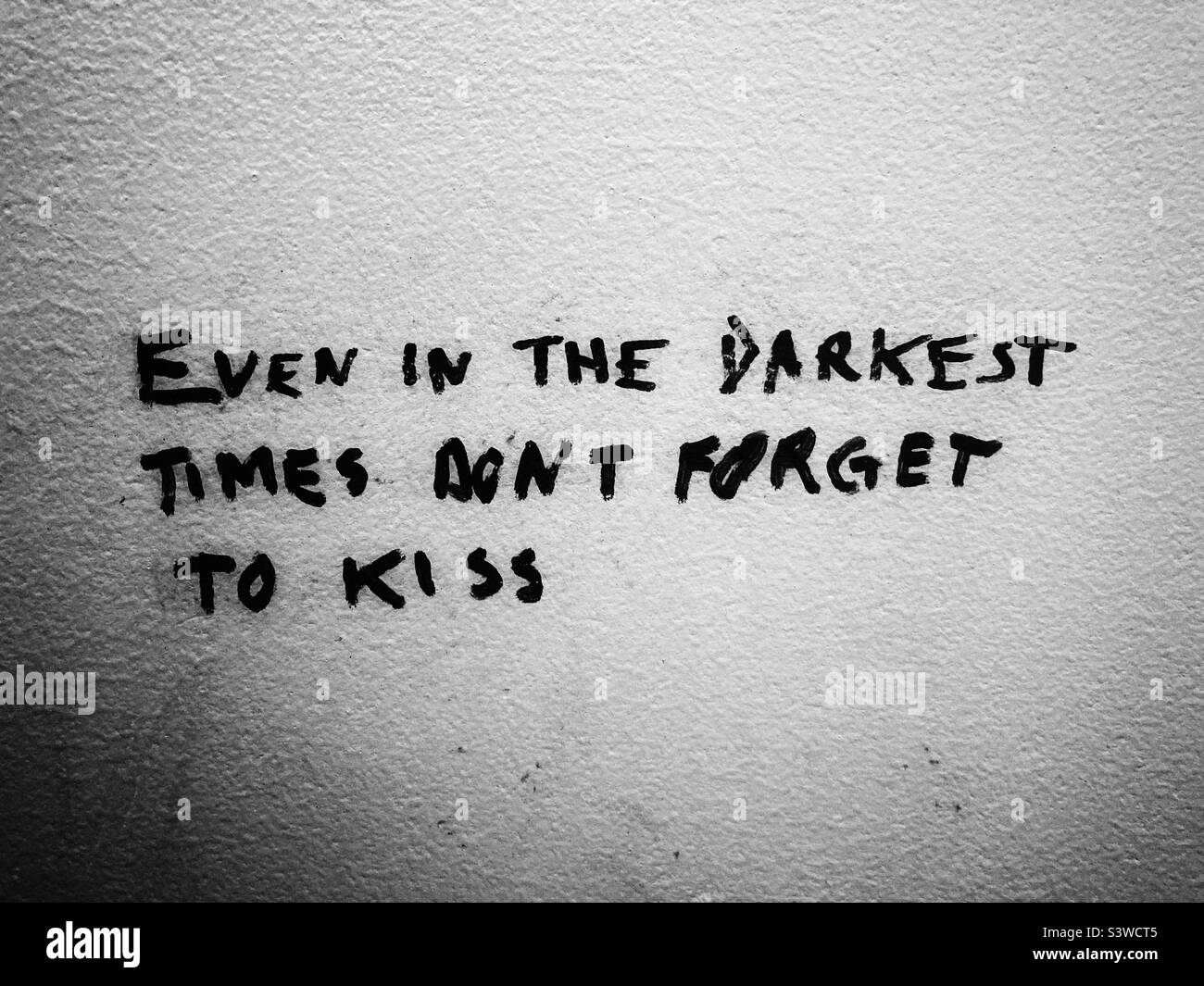 Ein Slogan auf einer Toilettenwand: Vergessen Sie auch in den dunkelsten Zeiten nicht, zu küssen Stockfoto