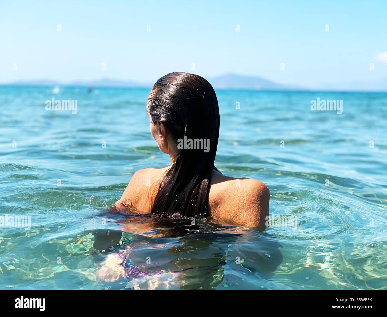 Junge Frau im blauen Meerwasser Stockfoto