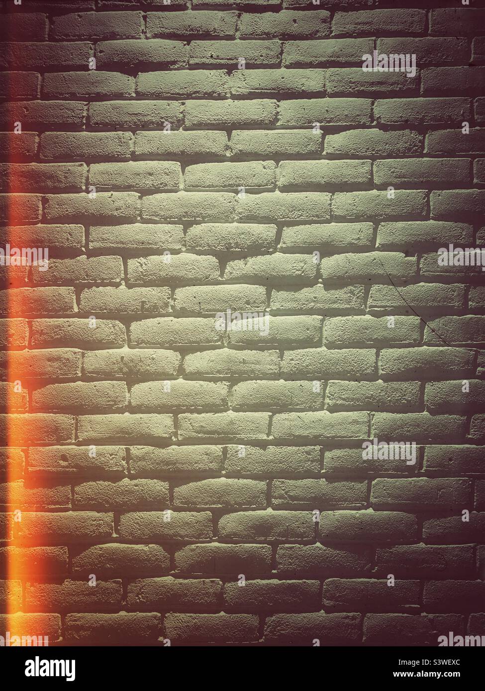 Ein Backsteinwand-Textur-Hintergrund mit Lichtreflexfilter und Grunge-Effekt - Smartphone-aufgenommenes Stockfoto