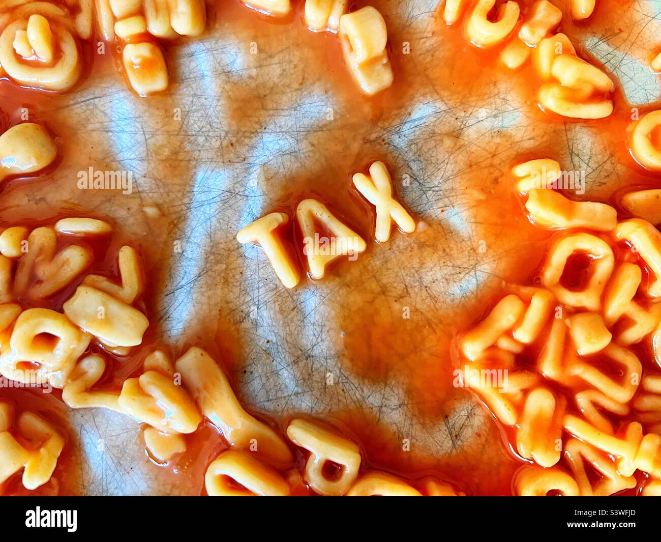 Das Wort Tax in Alphabetti-Nudeln auf einem Teller geschrieben - Smartphone-aufgenommenes Stockfoto