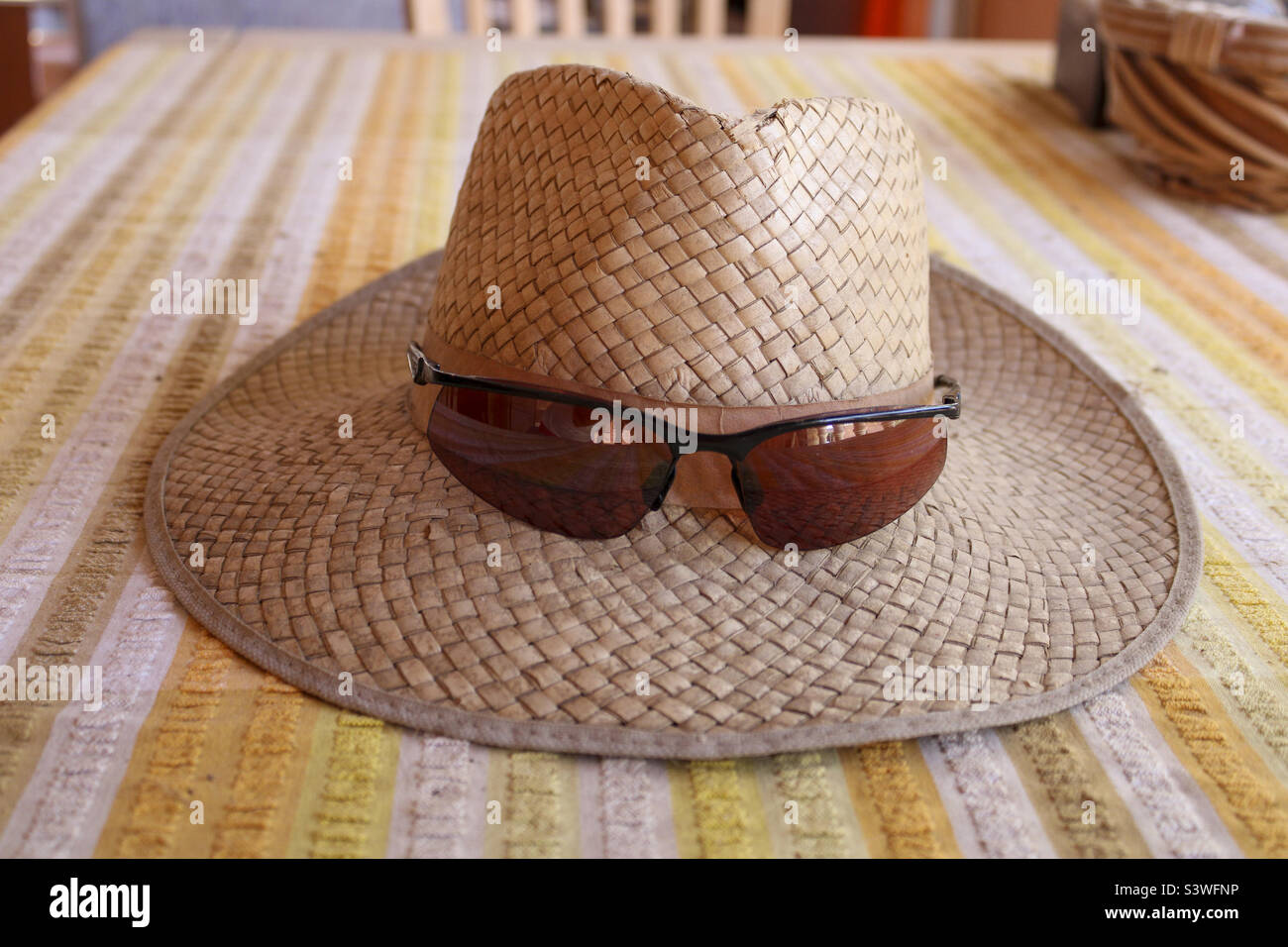 Catral, Spanien.10-08-22: Die Temperaturen steigen an diesem Wochenende bis auf 42 Grad. Alles, was Sie brauchen, ist ein Hut und eine Sonnenbrille. Hier auf einem Tisch mit gelbweißer Tischdecke - Smartphone-aufgenommenes Stockfoto