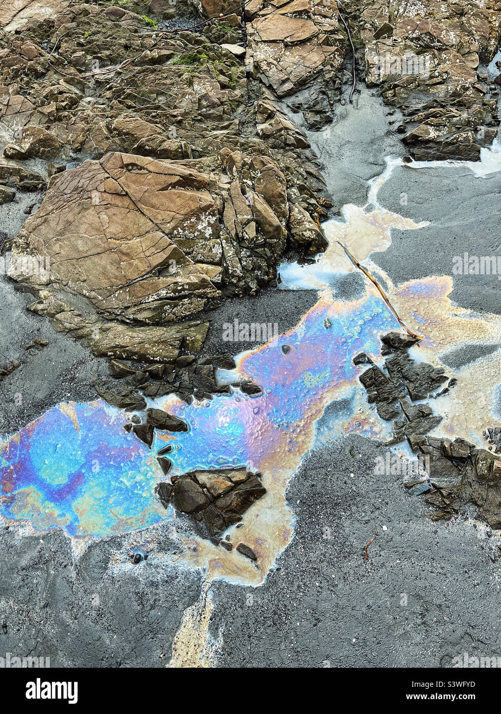 Ölpest erzeugt Regenbogenpools an einem Pacific Ocean Beach Stockfoto
