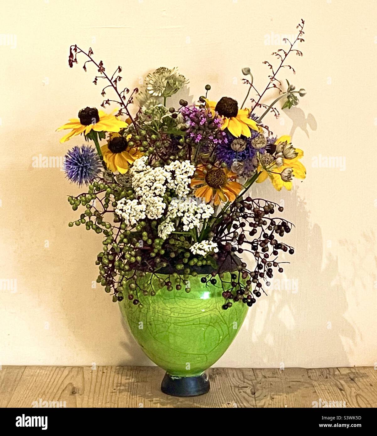 Grüne Vase mit Herbstblumen und Beeren Stockfoto