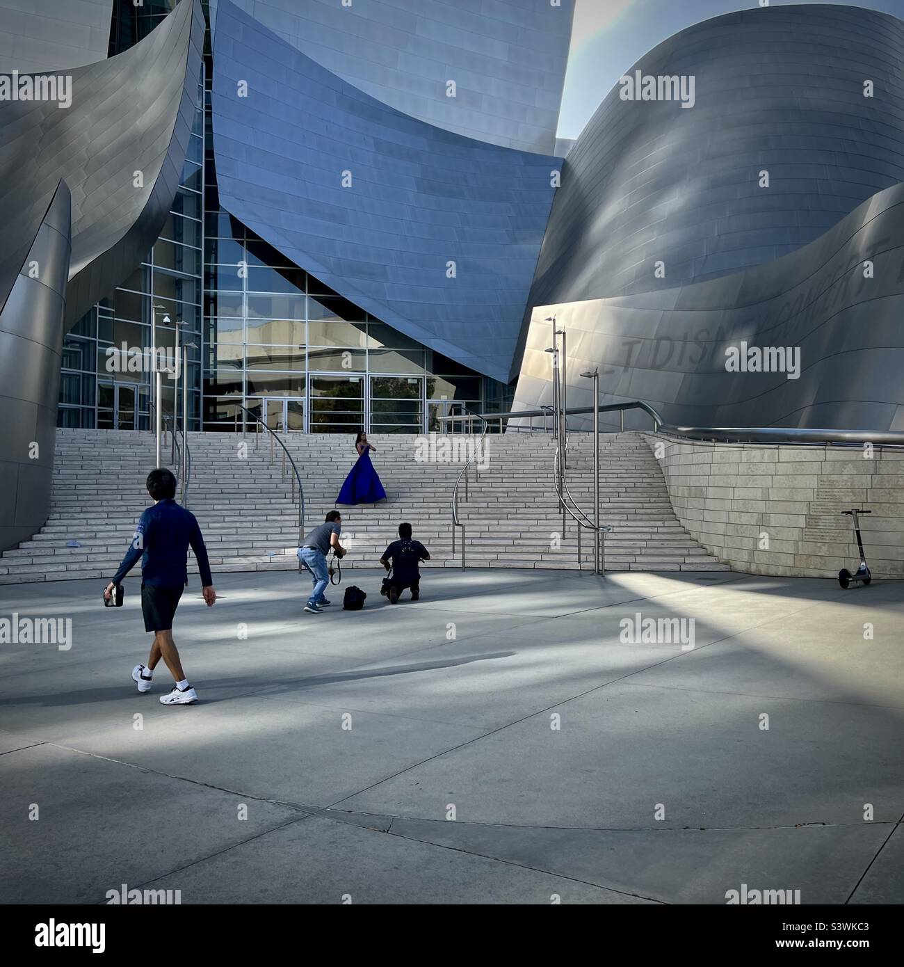 LOS ANGELES, CA, MAI 2022: Fotografen, die am späten Nachmittag auf einer Treppe vor der Walt Disney Concert Hall in Downtown Fotos von Frauen in fließendem blauem Kleid machen Stockfoto