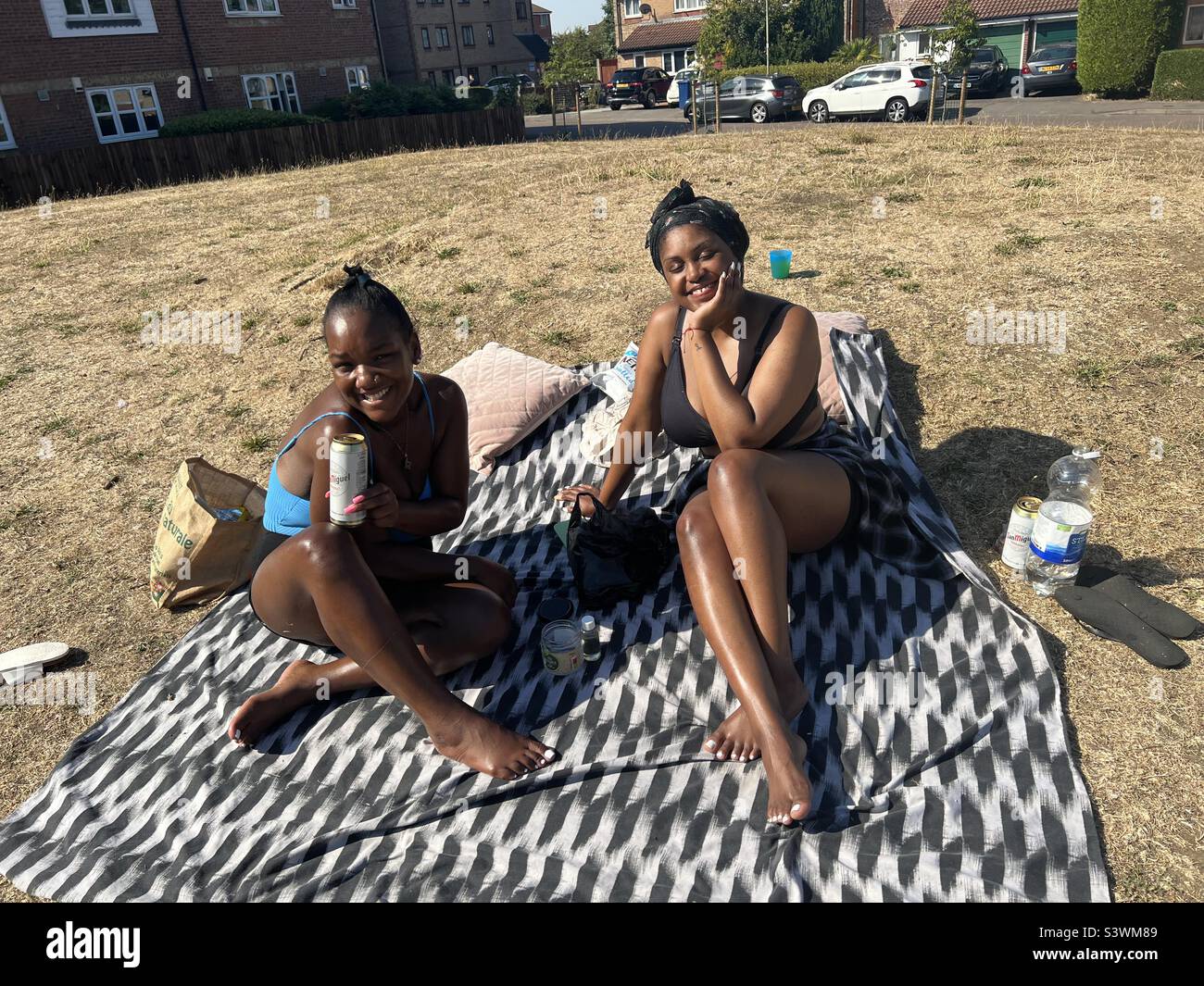 Frauen, die sich während der Hitzewelle in London auf der Wiese sonnten Stockfoto