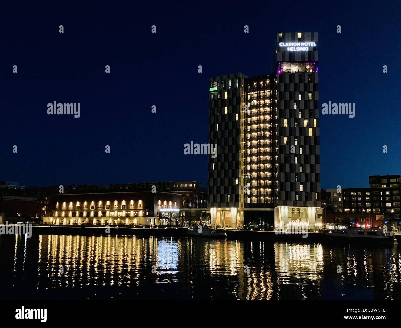 Clarion Hotel am Abend mit Lichtreflexionen im Wasser in Helsinki, Finnland - Smartphone-aufgenommenes Stockfoto