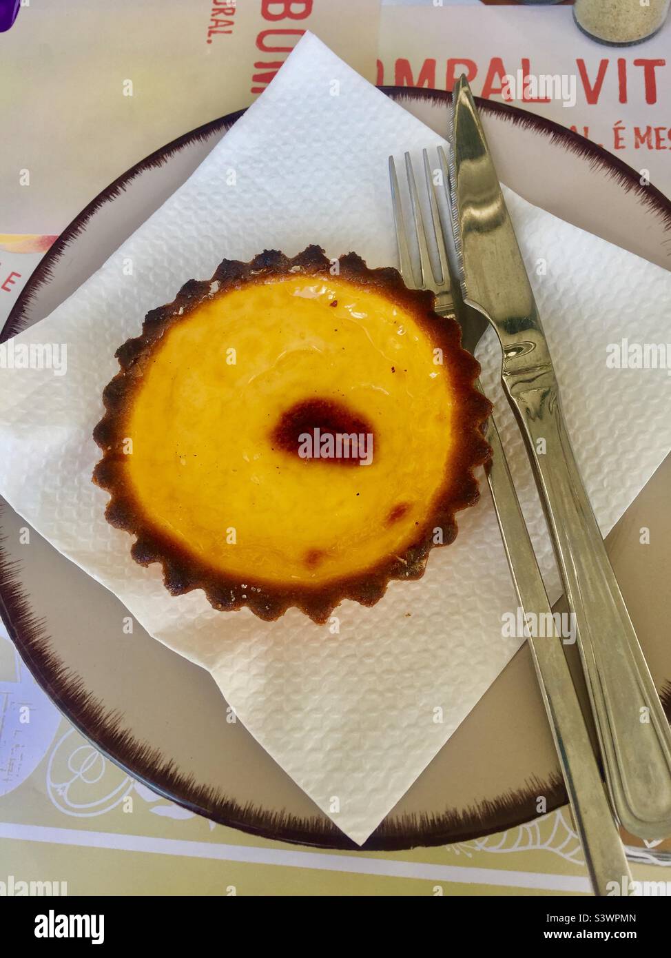 Portugiesische Pudding-Tarte auf weißem Gewebe und Teller mit Messer und Gabel. Stockfoto