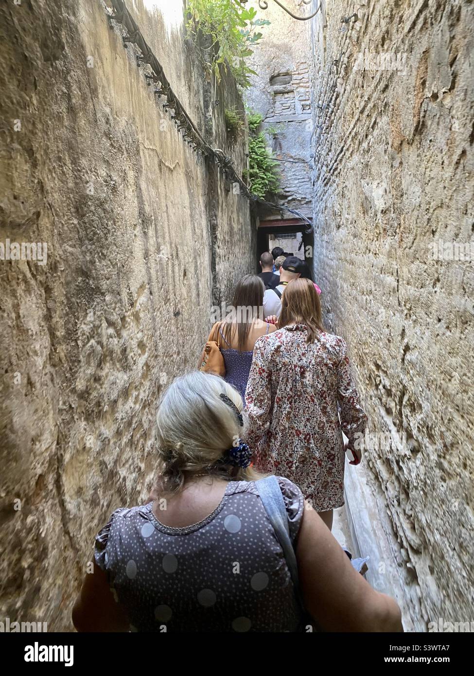 Medina von Fès schmale Gasse und europäische Touristen auf Führung in Fès, Marokko, Nordafrika Stockfoto