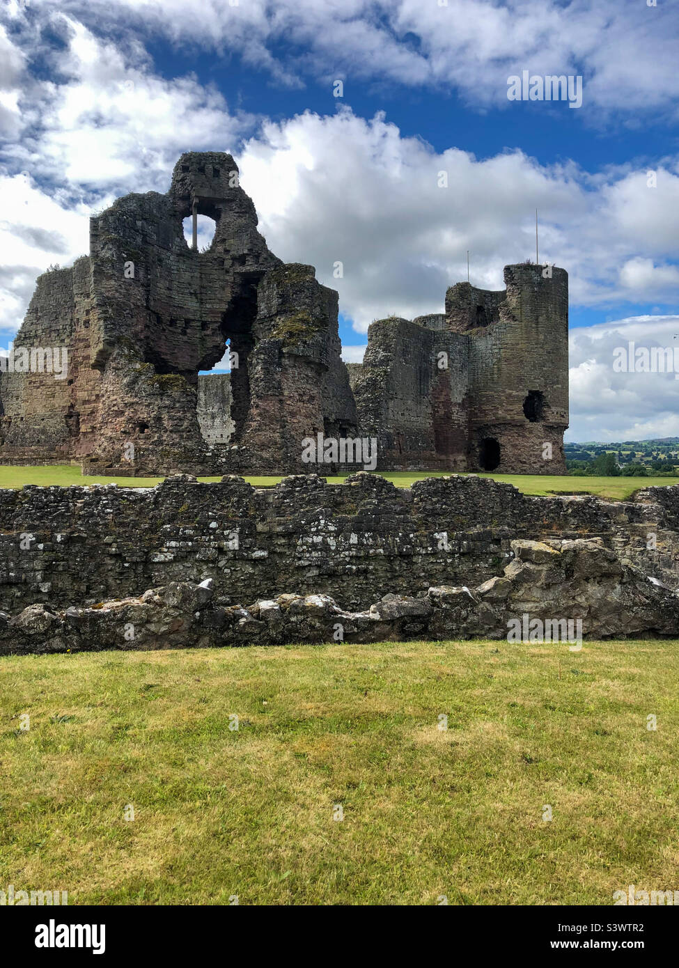 Die Ruinen der Burg Rhuddlan an einem sonnigen Julitag zeigen den Graben und die Überreste der Burg. - Smartphone-aufgenommenes Stockfoto