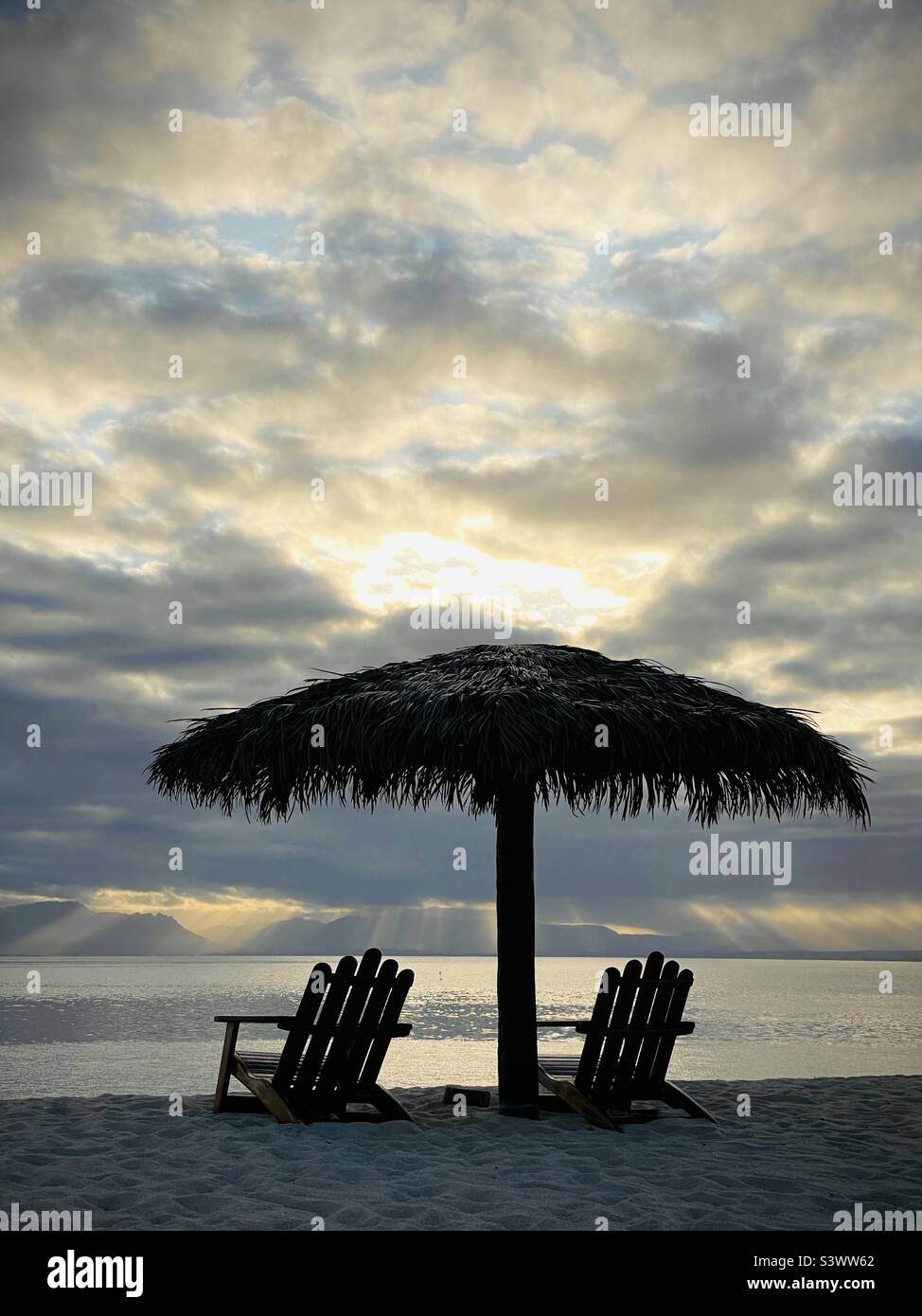 Zwei leere Strandliegen unter einem Palapa an einem frühen Sonnenaufgang in Fidschi. Tavarua Island Resort, Fidschi. Stockfoto